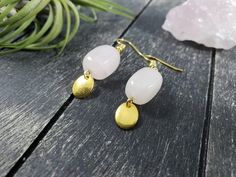 These boho dangle earrings feature 14mm x 10mm rose quartz nuggets with small 8mm x 10mm gold-plated oval charms dangling from the bottom. Rose Quartz is known as the stone of universal love, and is said to restore trust and harmony in relationships and encourage unconditional love. Rose Quartz purifies and opens the heart at all levels to promote love, self-love, friendship, deep inner healing, and feelings of peace. These lightweight earrings measure approximately 1 7/8 inches from the top of Rose Quartz Gemstone Dangle Earrings, Nickel-free Rose Quartz Dangle Earrings, Rose Quartz Drop Earrings For Jewelry Making, Pink Quartz Jewelry, Nugget Earrings, Geometric Rose, Rose Quartz Jewelry, Rose Gold Quartz, Rose Quartz Earrings