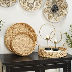 wicker baskets and candle holders on a black cabinet in front of a white wall