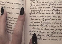 a woman's hand holding onto an open book with french writing on the pages