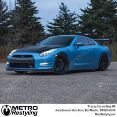 a blue sports car parked in front of some trees