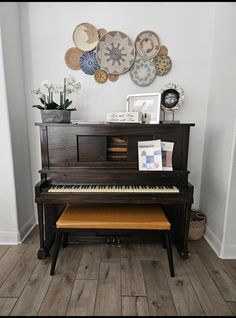 a piano sitting in front of a wall with plates on it