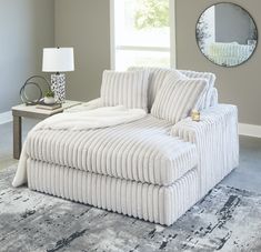 a large white couch sitting on top of a rug in a living room next to a window