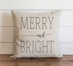 a merry and bright pillow sitting on top of a wooden floor next to a white wall