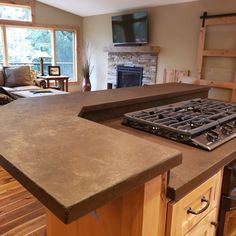 a kitchen counter with a stove top and oven in it's center island, next to a couch