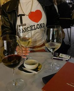 a woman sitting at a table with two glasses of wine