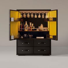 an open cabinet with liquor bottles and glasses on the top, in front of it