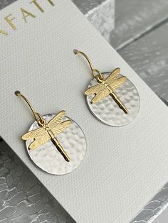 "The round brass drop is plated with a glossy silver alloy which is a mix of different base metals. The finish is glossy because it is rack plated. This means that the pieces are hand hung so they receive the optimal amount of coverage. Overlapping is an 18K gold plated dragonfly charm which compliments the silver round drop. The look is completed with a dragonfly neck piece. The dragonfly is plated in 18 K gold with a silver base metal chain. The following options are available: 1) Earrings 2) Nickel-free Gold Dragonfly Earrings, Gold Nickel-free Dragonfly Earrings, Silver Dragonfly Necklace, Mixed Metal Earrings, Dragonfly Charm, Dragonfly Necklace, Dragonfly Earrings, Earrings And Necklace, Fall Earrings