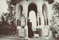 an old photo of a woman standing in front of a gazebo