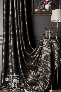 a black and silver curtain with an intricate design on it in front of a painting