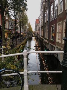 a bike parked on the side of a street next to a river with lights strung from it