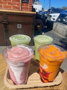 three different colored drinks sitting on top of a wooden tray