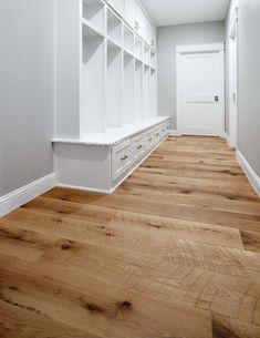 an empty room with white shelves and wood flooring on either side of the door