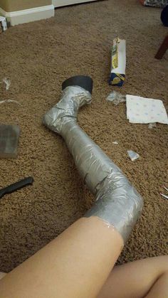 a woman laying on the floor with her leg wrapped in duct tape