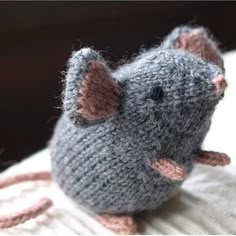 a gray knitted mouse sitting on top of a bed