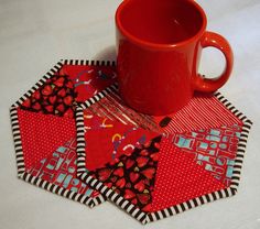 a red coffee cup sitting on top of a patchwork coaster