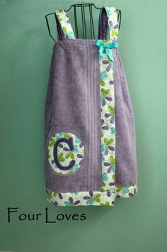 a purple towel hanging on a green wall with the letter c in blue and white