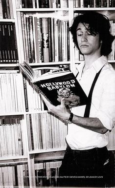 a man holding a book in front of a bookshelf