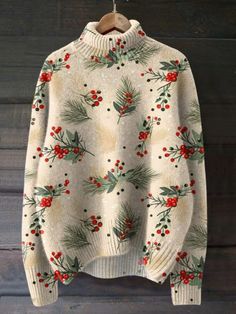 a white sweater with holly and red berries on it hanging from a wooden hanger