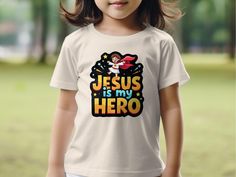 Celebrate faith with the "Jesus is My Hero" kids T-shirt. This inspirational tee features a joyful design perfect for boys. Ideal for church events, Sunday school, or everyday wear. A wonderful Christian gift that spreads positivity and faith. Made for comfort and durability, inspiring kids to embrace their beliefs with pride. Uplift any child's wardrobe! This quality t-shirt with an appealing design is perfect for your cherished son or daughter, nephew or niece, or friend of the family. It also Children Bible, Joyful Design, Inspirational Graphic Tees, Church Events, Inspirational Tees, Toddler Mom, Inspiration For Kids, Girls Show, Jesus Is