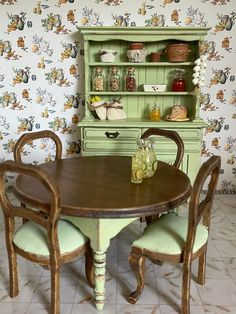 a dining room table with four chairs and a hutch in the backround