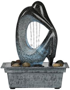 an artistic sculpture sitting on top of a planter filled with rocks and water droplets