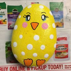 an easter egg painted to look like a yellow chick with white dots and pink nose