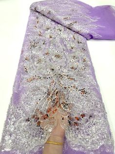 a person is holding onto a purple cloth with sequins on it and the fabric has been folded over