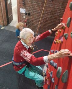 an older woman climbing up the side of a wall