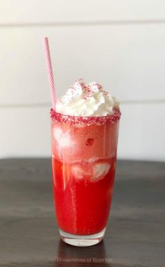 a red drink with whipped cream and sprinkles in it on a table