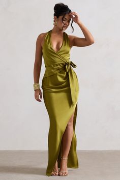 a woman in a long green dress with a slit down the side and her hand on her head