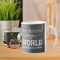 a white coffee mug sitting on top of a wooden table next to a pair of glasses