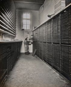 an old black and white photo of two people in a room full of mail boxes