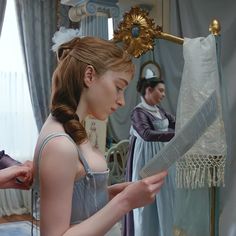 a woman is getting her hair combed in front of a mirror while another woman looks on