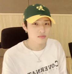 a young man wearing a baseball cap sitting in front of a computer desk and chair