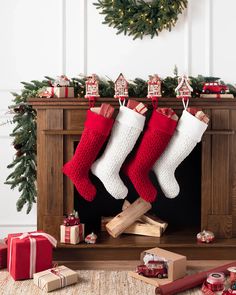 christmas stockings hanging from a fireplace with presents underneath