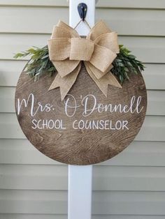 a wooden sign with a bow hanging from it's side on the front door