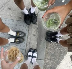 several people are standing on the sidewalk with their feet up and holding bowls of food