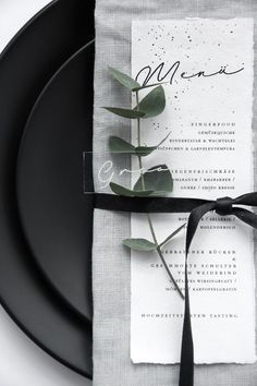 a black and white plate with a napkin tied around it that has a flower on it