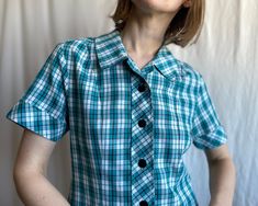 A-line mini dress in turquoise, black and white check, by Australian uniform manufacturer. Short sleeves, notch collar, with buttons down the front and martingale belt at back. One side pocket with zipper closure. ✏️ TAGS HAMBOURS Proudly Australian since 1936 65% polyester 35% rayon Made in Australia ✂️ CONDITION  Good vintage condition. Cleaned and ready to wear. 📏 MEASUREMENTS  Measured laying flat, please double for circumference: length  36 1/2" 93cm shoulders  14 1/2" 37cm bust 17 1/4" 44 Fitted Button-up Plaid Dress, Fitted Button-up Plaid Dress With Buttons, Fitted Plaid Button-up Dress, Classic Fitted Plaid Dress With Short Sleeves, Fitted Classic Plaid Dress With Short Sleeves, Fitted Plaid Dress With Buttons For Work, Fitted Plaid Dress With Button Closure For Summer, Classic Fitted Plaid Dress With Buttons, Fitted Plaid Dress With Buttons