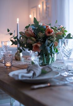 the table is set with candles and flowers in vases, plates and napkins