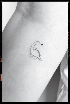 a small dinosaur tattoo on the left side of the right arm, with a tiny heart in it