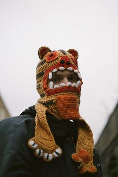 a man wearing a knitted hat and scarf with an animal head on it's face