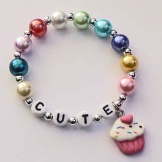 a bracelet with charms that says cute and a cupcake charm on the clasps