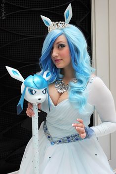 a woman with blue hair is dressed up as an anime character and holding a toy