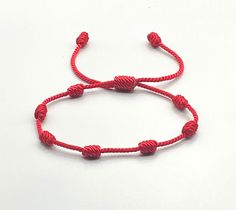 This bracelet is linked to a sequence of 7 Knots, each of which symbolizes a spiritual dimension that ends up infusing your reality. Features: (1) 1.5mm Twisted Nylon Cord (2) Each knot is tightly woven to prevent fraying or becoming loose. (3) Bracelet is made to fit most wrist sizes. Sizes can be customized on request. Adjustable Red Bracelet For Blessing, Traditional Red Bracelets For Blessing, Symbolic Red Bracelet Jewelry, Red Symbolic Bracelet Jewelry, Red Symbolic Handmade Bracelets, Adjustable Red Rosary Bracelet For Friendship, Adjustable Red Rosary Bracelet, Adjustable Red Spirituality-inspired Bracelet, Symbolic Red Jewelry For Friendship