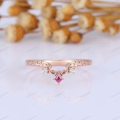 a pink diamond ring sitting on top of a table next to some dried flowers and leaves