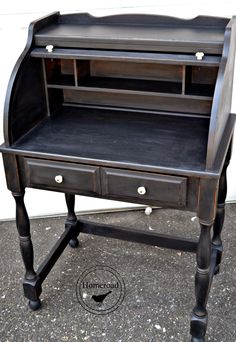 an old fashioned desk with black paint and drawers