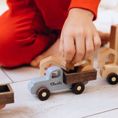 a young child playing with wooden toys on the floor in front of him and his truck