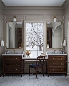 a bathroom with two sinks, mirrors and a chair in front of a large window