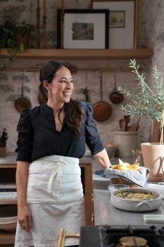 a woman standing in front of a counter with food on it and smiling at the camera